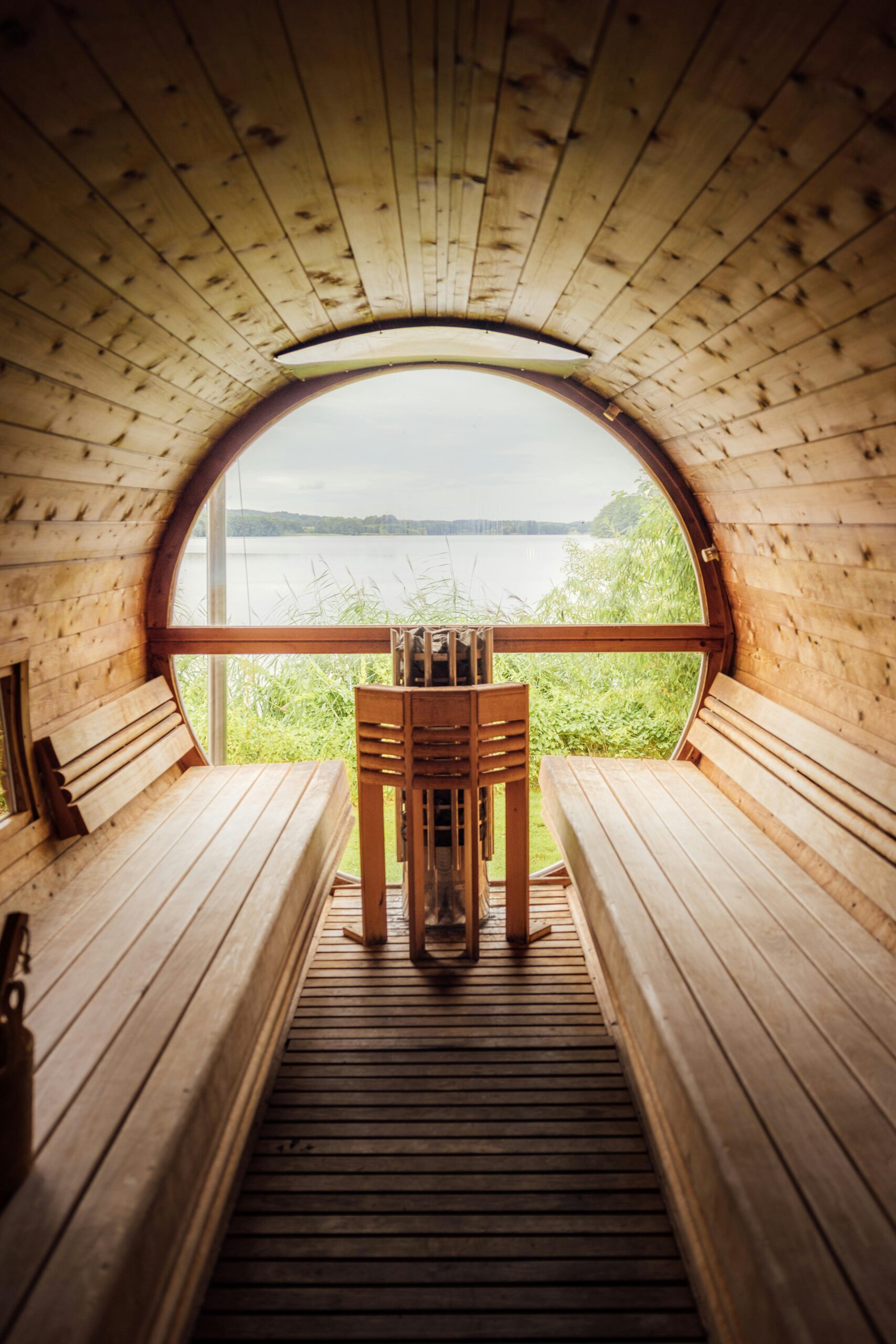 Cozy wooden sauna interior with a serene lake view, perfect for relaxation.